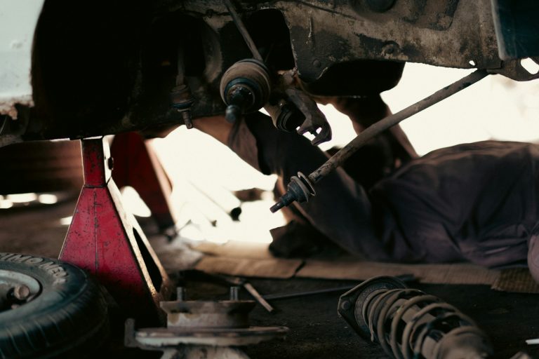 tahamie-farooqui-K5624F8cipE-unsplash A man working on a car under a vehicle