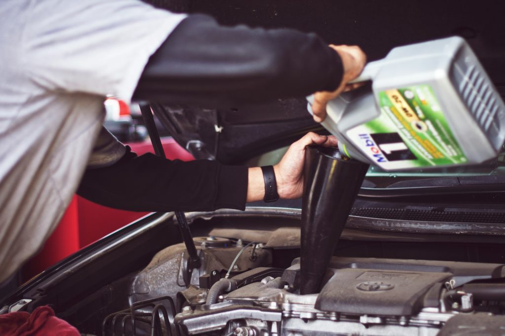 tim-mossholder-V37iTrYZz2E-unsplash Man refilling motor oil on car engine bay
